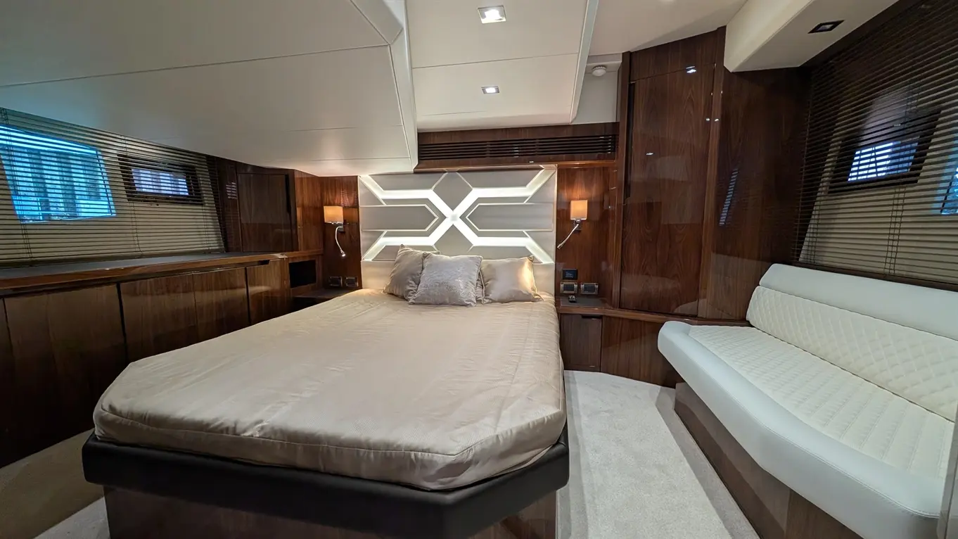 Luxury yacht cabin featuring a large bed, stylish wood furnishings, ambient lighting, and a plush white sofa.